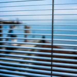 Blurred outdoor scene visible through modern window blinds, creating a tranquil ambiance.